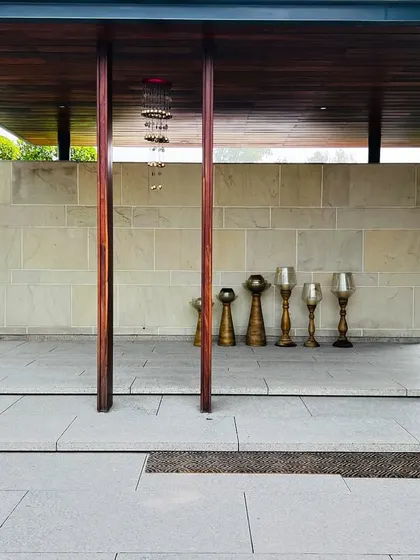 A pergola over the entryway of the Sultanpur farmhouse, with decorative candle holders lining the stone wall.