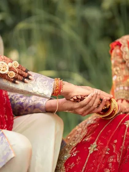 A detail shot of the bride and groom's hands, adorned with intricate henna and wedding rings, a symbol of their union.