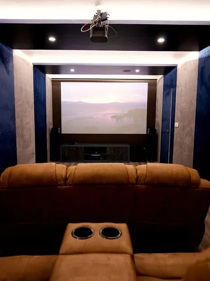 A dedicated home theater room designed for the ultimate cinematic experience, with plush recliner seating, acoustic wall paneling, and a ceiling-mounted projector.