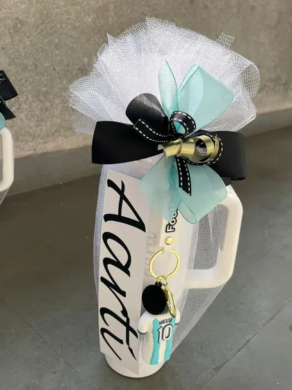 A personalized mug for "Aarti," featuring a football-themed keychain. We can customize these favors to match any party theme, from sports to superheroes.