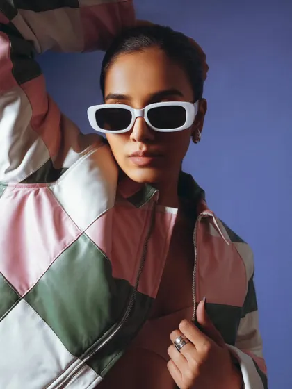 A close-up shot highlighting the stylish sunglasses and the texture of the patchwork jacket. A great shot for commercial fashion.