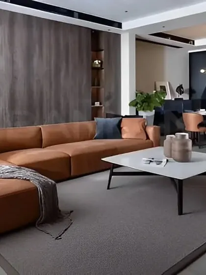 We designed this open-plan living and dining area with a cohesive aesthetic. The space features a comfortable tan leather sectional sofa, a minimalist coffee table, and dark wood paneling that adds warmth and texture.