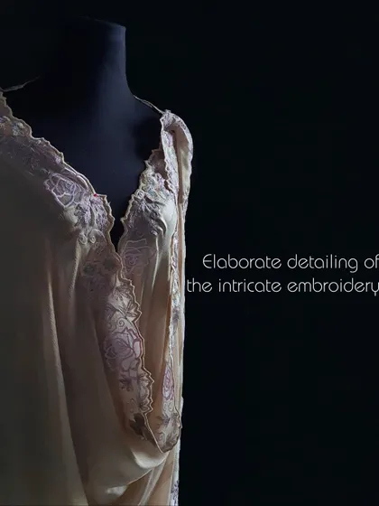 This image showcases the elaborate detailing of the intricate floral embroidery on a shimmering, striped fabric, ready to be tailored.