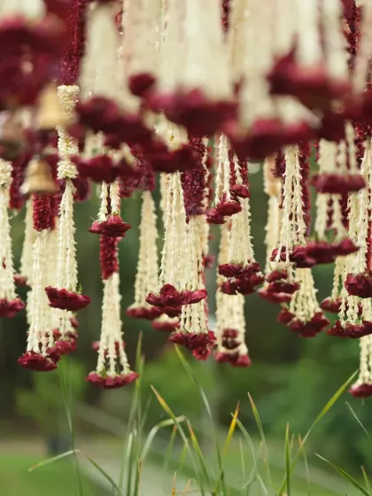 A detailed shot of the floral hangings made from tuberose and red flowers, a key element of the Banaras Ghat mandap ceiling.