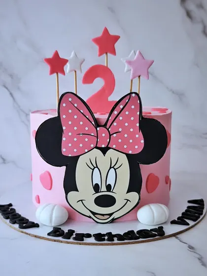 A classic Minnie Mouse cake for a 2nd birthday. This pink black forest cake features Minnie's iconic face and bow, decorated with cute polka dots and stars.