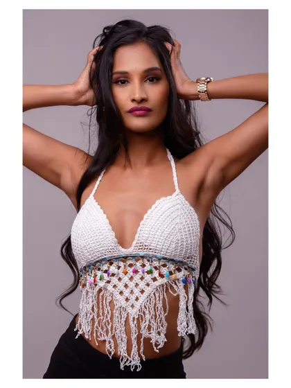 A stylish studio portrait of a model in a crochet top. Her pose is strong and confident, showcasing both the outfit and her personality.
