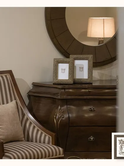 A pair of simple, elegant photo frames sit atop a classic chest of drawers. Their understated design allows the beauty of the carved wood furniture and the memories within the frames to shine.