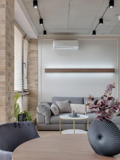 A minimalist living and dining area with exposed brick texture, a concrete ceiling, and modern furniture for an industrial-chic look.