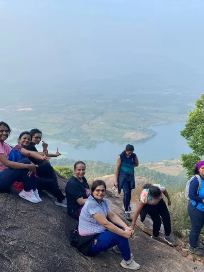 A few members of the family trek group taking a break on a large rock overlooking a lake.