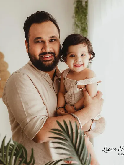 A father and his baby share a smile in this warm and happy portrait. This captures a beautiful, natural interaction during a family shoot.