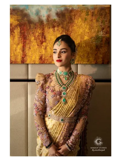 A stunning portrait of Krishna against an artistic backdrop. The warm lighting enhances the golden tones in her saree and the rich red of her lips, creating a picture of timeless elegance.