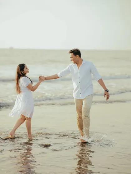 Leading each other into a new chapter. A beautiful, dynamic shot of a couple enjoying their pre-wedding photoshoot on the beach, filled with movement and joy.
