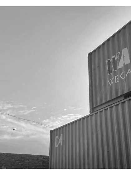 Two containers stacked, forming a multi-story structure. This black and white shot highlights the raw, geometric beauty of the corrugated steel before modification.