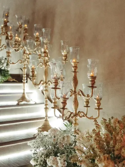 Elegant candelabras line the staircase, their warm light creating a romantic and welcoming pathway for guests, showcasing the importance of lighting in setting the mood.