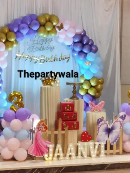 A princess theme for twins, featuring a large balloon arch and two character cutouts.