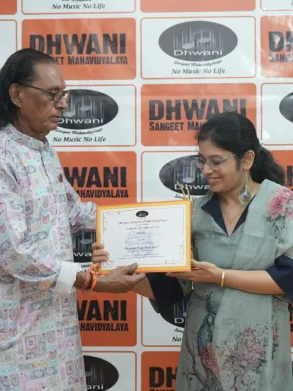 A guru presents a certificate to his adult student, recognizing her dedication.
