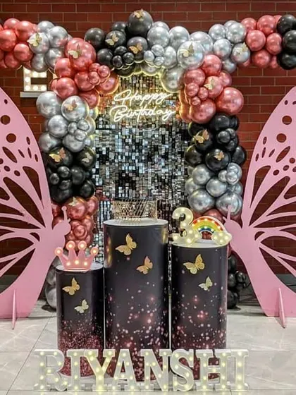 A glamorous butterfly themed birthday party with a shimmer wall and large pink butterfly wings for a perfect photo backdrop.