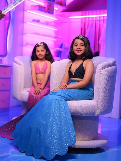 Two girls dressed as mermaids pose in the spa room, showing off their magical transformation.