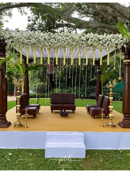 Set against a lush green backdrop at the Signature Club Resort, this traditional mandap exudes grace. I used majestic wooden pillars, a canopy of white chrysanthemums, and hanging temple bells to create a serene and sacred space.