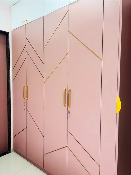 A close-up showing the detail of the gold inlay and the sleek, modern handles on the pink wardrobe.
