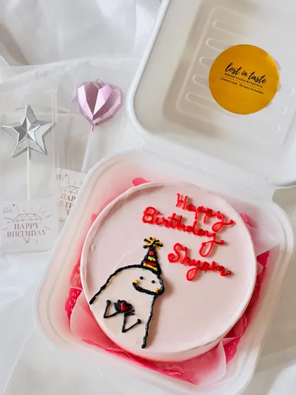 A cute and simple character design for a birthday. This pink bento cake features a cartoon figure in a party hat, ready to celebrate.