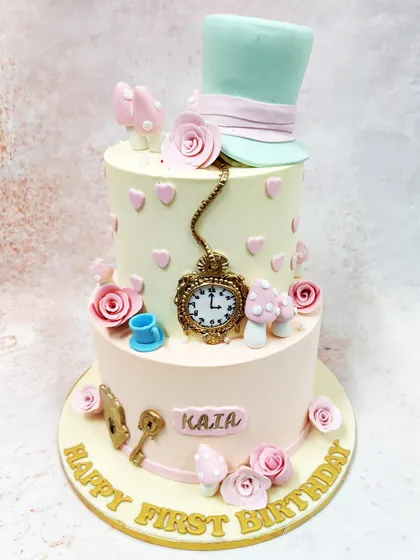We invite you down the rabbit hole with this whimsical two-tiered Alice in Wonderland cake. Adorned with the Mad Hatter's hat, a pocket watch, and other iconic elements from the story, this pastel-colored creation is perfect for a magical first birthday tea party.