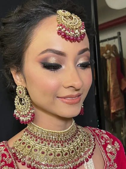A close up of this stunning bridal glam. The eyes are the focus, with a beautiful blend of gold glitter and dark brown smokey shadow, paired with a glossy nude lip.