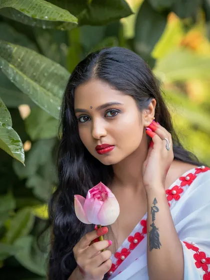 A close-up beauty shot with a traditional touch. The lotus flower and the subject's expression create a serene and poetic image, blending nature with ethnic style.