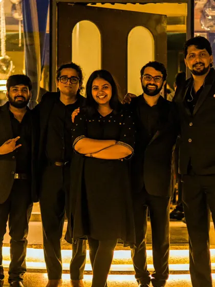 Five of us pause for a band portrait after a multilingual corporate evening in Bengaluru.