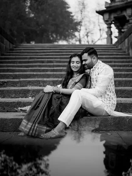 A serene black and white portrait of Ankush and Aishwarya, with their reflection captured in the water below.