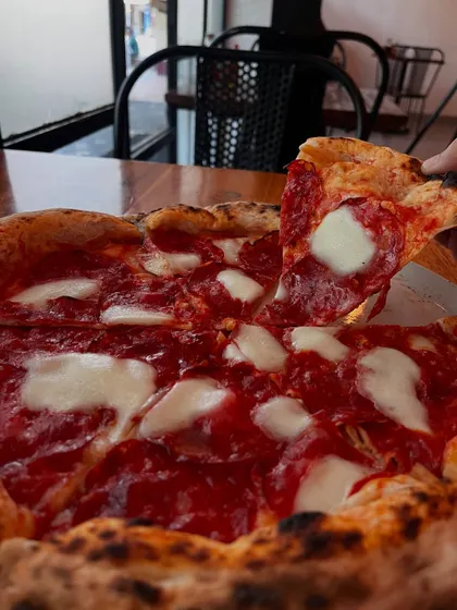 A perfect slice of pepperoni pizza being lifted, showing off the melted cheese and crispy crust.