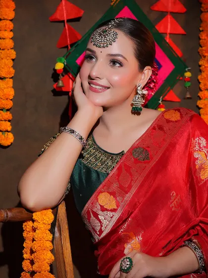 A smiling portrait in the red Banarasi saree, paired with a contrasting green blouse and traditional jewellery.