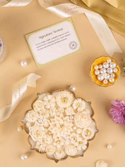 A detailed shot of the white floral candle, focusing on its delicate craftsmanship and the brand's signature aroma card.