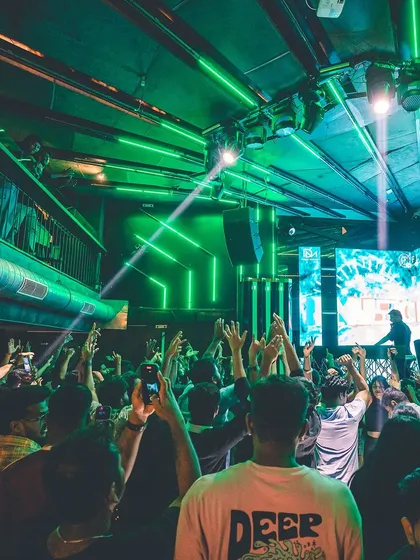 Green lasers cut through the darkness above a packed dance floor. This image captures the electrifying atmosphere of a peak-time set.