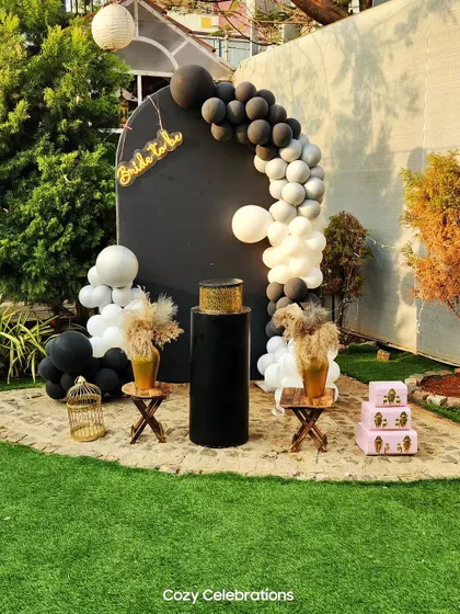 For a modern and chic bride, this black and white theme is a standout choice. The decor features a bold black backdrop with a contrasting white and black balloon arch and rustic pampas grass details.