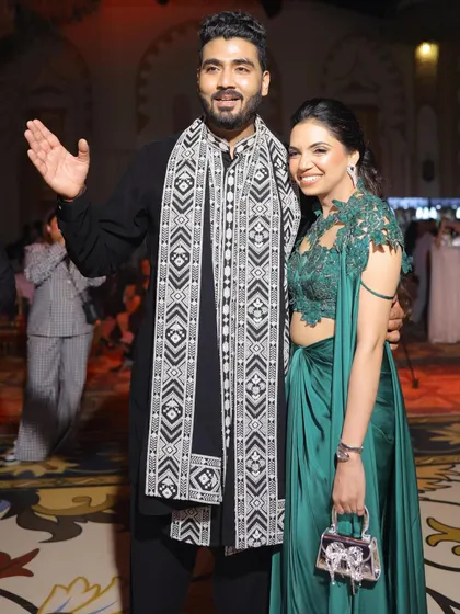 Nikita and Abhinav at their Sufi night engagement party. Her dark green gown and his classic black kurta with a patterned shawl create a stylish and complementary couple's look.