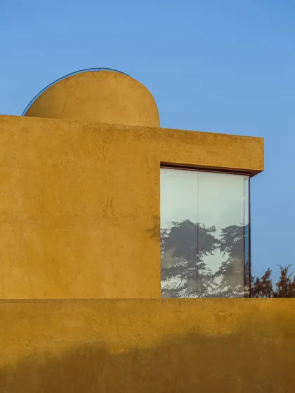 A large window reflects the surrounding trees, making the forest an integral part of the building's facade.