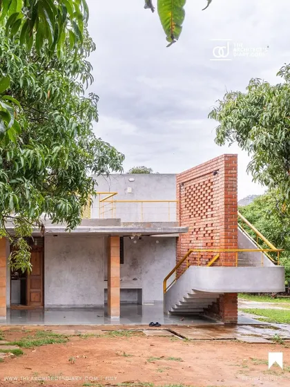 The external staircase at "Aamra," featuring a perforated brick jaali wall. This element is both functional, providing safety, and decorative, casting intricate shadows while allowing for ventilation.