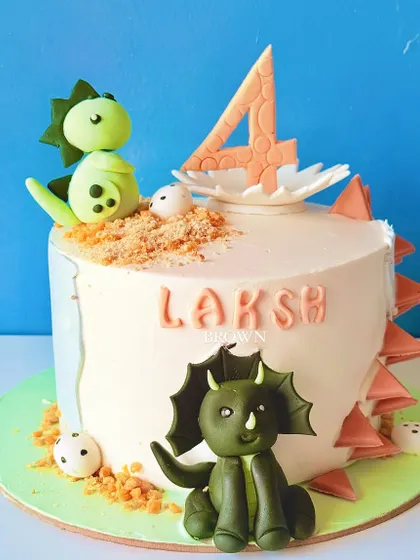 A cute dinosaur-themed cake for a 4th birthday. This design features friendly fondant dinosaurs, a nest with eggs, and edible "dirt" for a fun, prehistoric look.