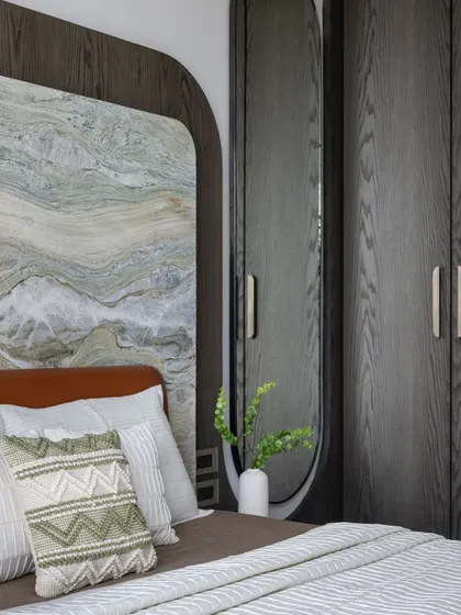 A different angle of the bedroom with the stone and wood headboard, showing how the textures are layered to create a cozy and stylish space.