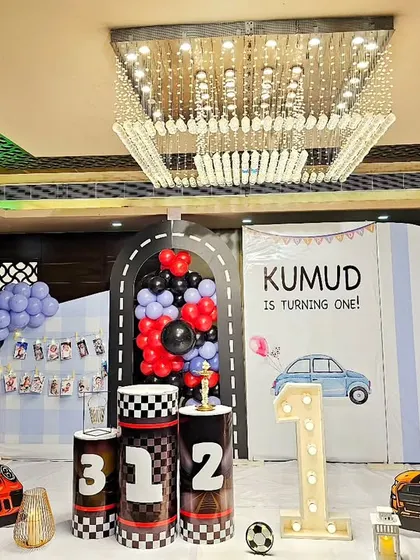 A high-speed car-themed first birthday. This setup features sports car cutouts, a racetrack-inspired backdrop, and checkered flag details.