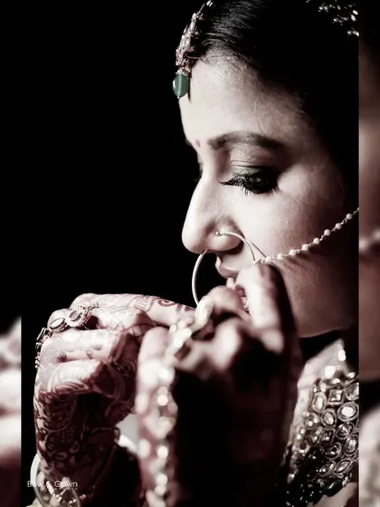 An artistic, high-contrast bridal portrait. The focus on the bride against a dark background creates a dramatic and beautiful image that highlights her features.