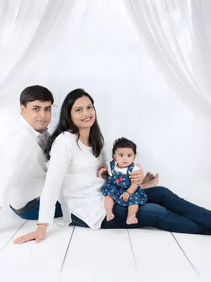 A sweet family portrait with the baby sitting comfortably on her mother's lap. The coordinated denim and white outfits give it a classic, cohesive feel.