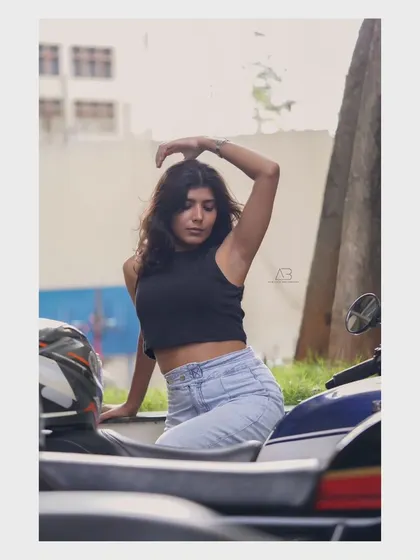A candid street-style shot, with the model posing near a scooter. It feels spontaneous and captures a slice of city life.