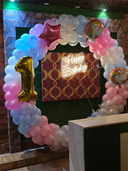 This first birthday setup features a balloon ring in pink, blue, and white. I added a number '1' foil balloon and a "Happy Birthday" neon sign to complete the look.