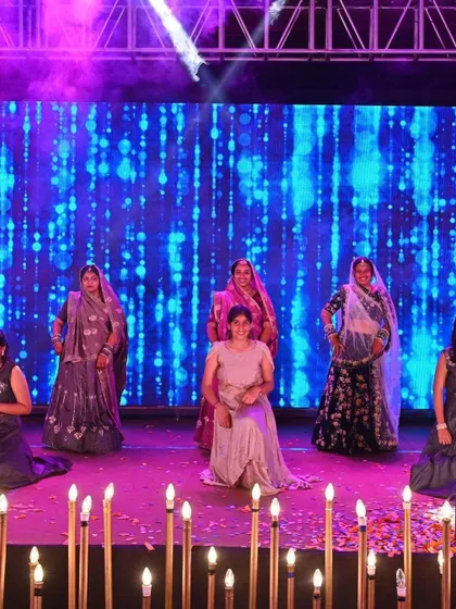 A beautifully staged moment from a ladies' sangeet performance. The combination of traditional attire, coordinated poses, and stage lighting creates a truly elegant picture.