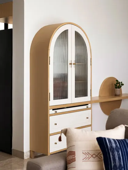 This custom-designed pooja unit features an arched top, fluted glass doors, and a continuation ledge, blending seamlessly with the living area.