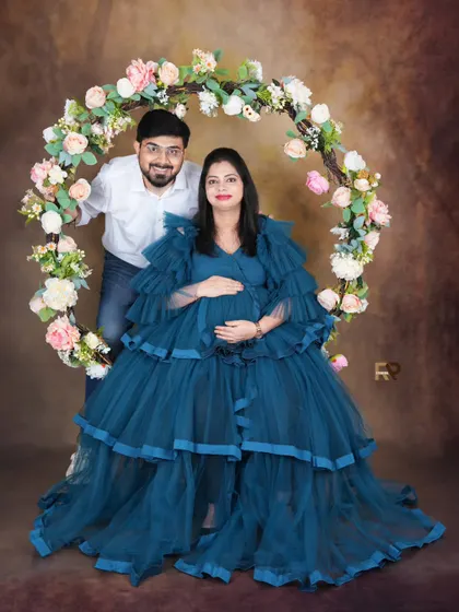 A happy couple portrait. The parents-to-be are all smiles, framed by our beautiful floral hoop prop. The mom-to-be's blue gown adds a lovely pop of color.