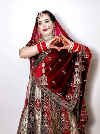 Another joyful shot of the bride making a heart shape with her hands, this time showing more of her beautiful lehenga.