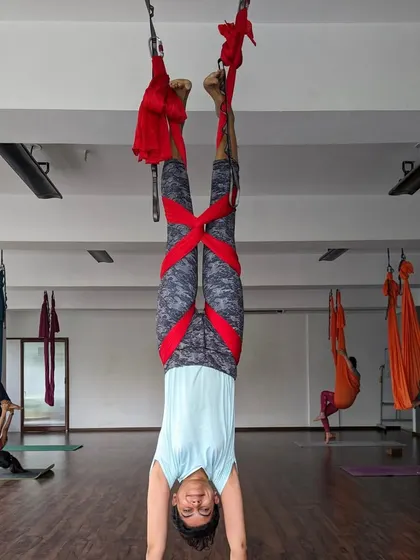 Another student mastering an inverted pose with the help of the hammock, surrounded by fellow practitioners.
